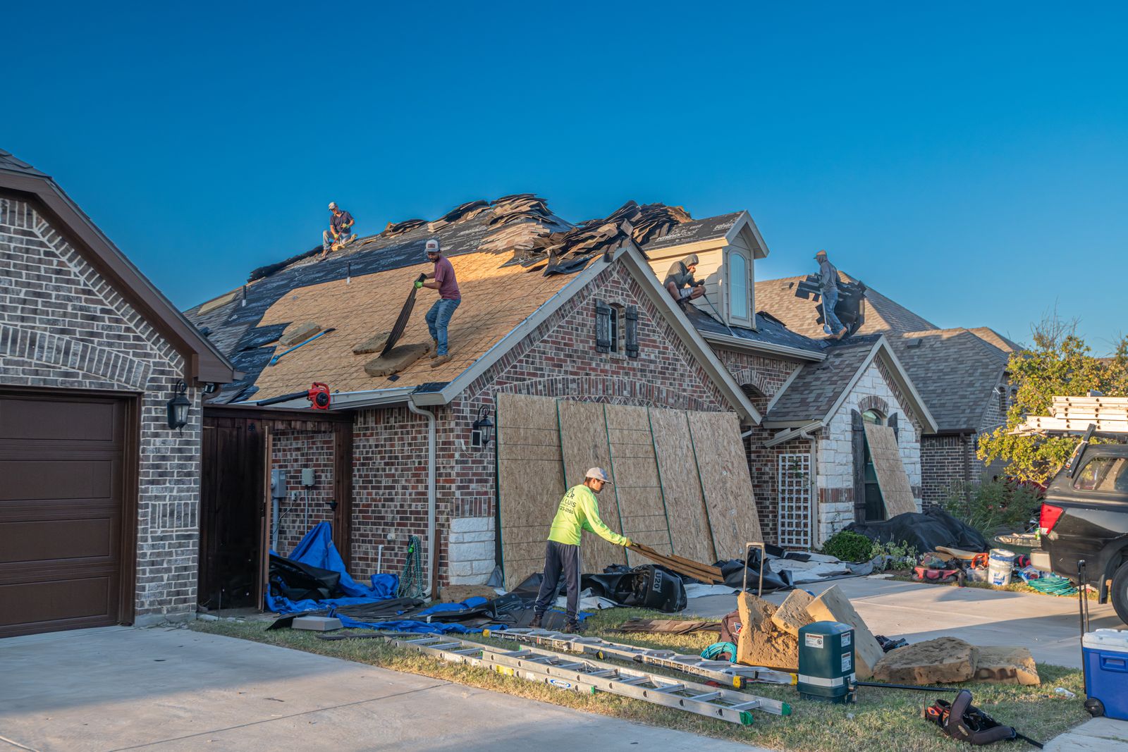 Storm-damaged home mid-restoration — roof torn off and windows boarded after a storm
