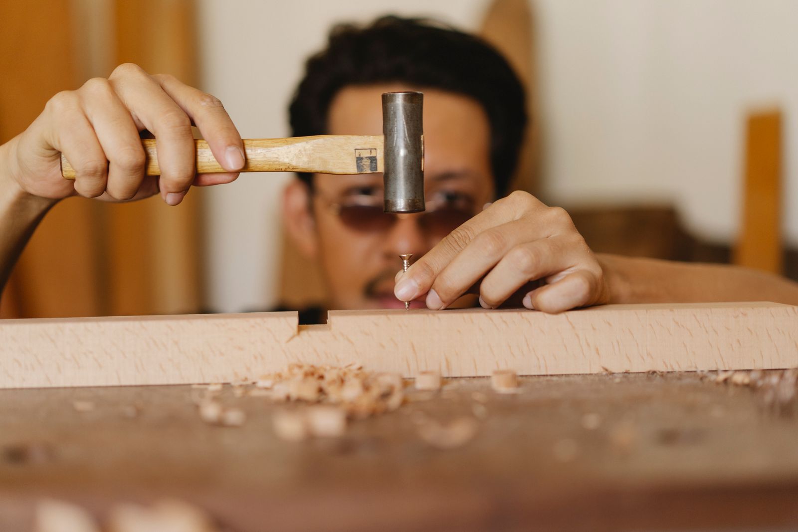 Close-up of hands driving a nail into fine wood joinery