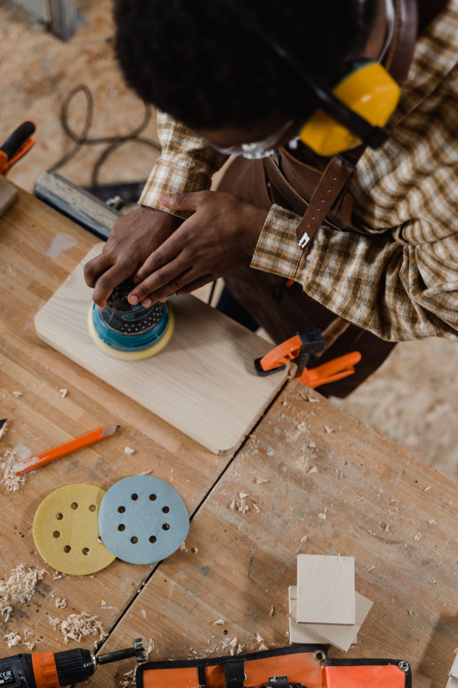 Overhead view of a craftsman sanding a board with tools laid out